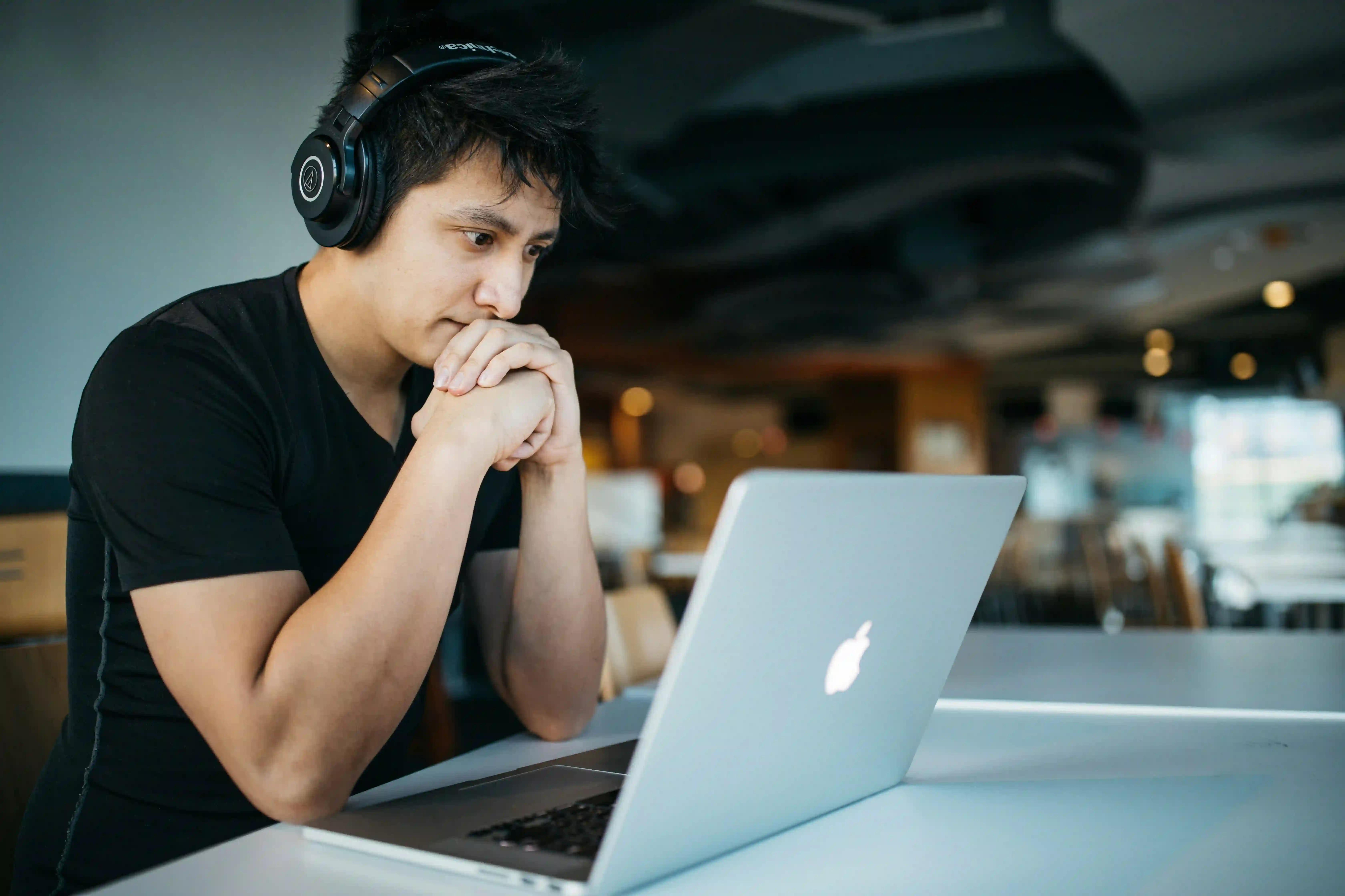 A student wearing a headphone looking at a laptop and studying